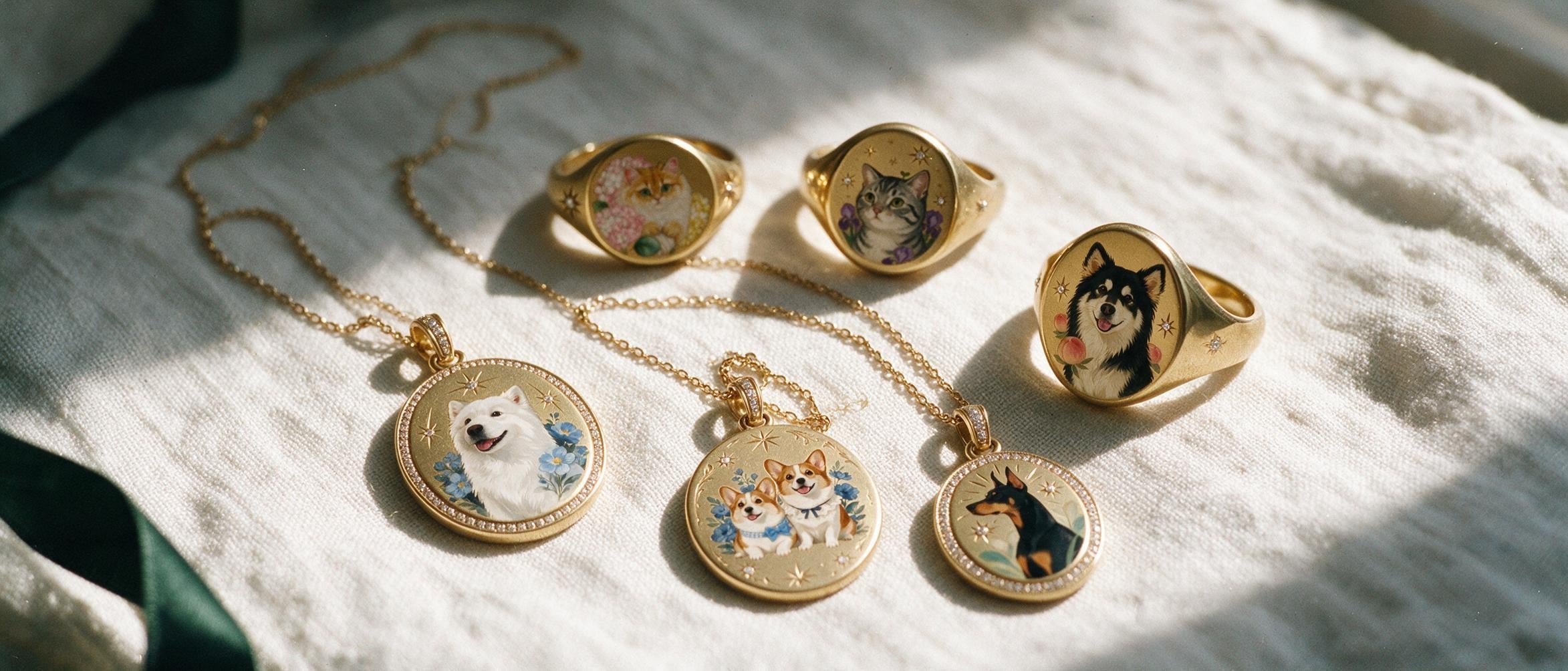 Six hand-painted enamel pieces in gold — pet portrait pendants and signet rings on linen